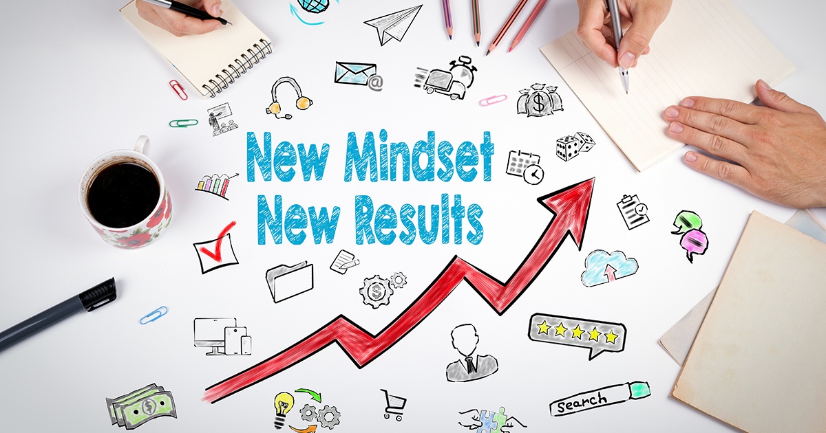 A motivational workspace scene featuring the phrase “New Mindset New Results” written in bold blue text. Surrounding the words are colorful hand-drawn doodles representing business and productivity — such as gears, money, a calendar, speech bubbles, a magnifying glass, and a five-star review bubble. A red upward arrow runs through the center, symbolizing growth and progress. On the sides, a person’s hands are shown writing on notepads, with coffee, pens, and paperclips completing the creative desk setup.